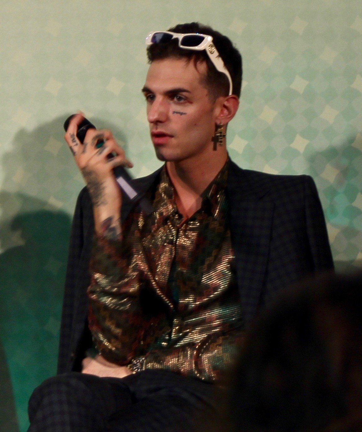 Achille Lauro con occhiali da sole bianchi tra i capelli e camicia dorata