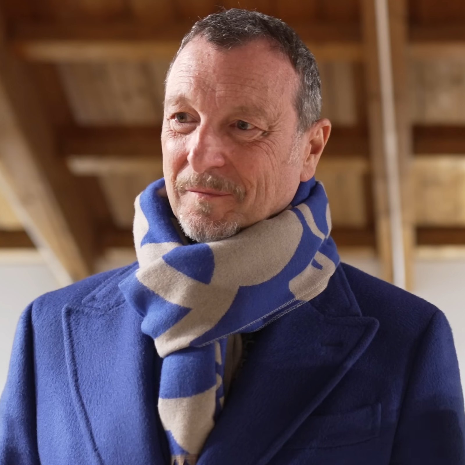 Amadeus con cappotto blu e sciarpa guarda di lato