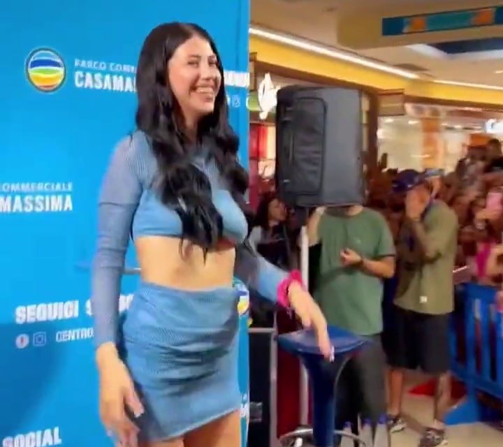 ANNA sorride durante un incontro con i fan, capelli lunghi neri e completo azzurro