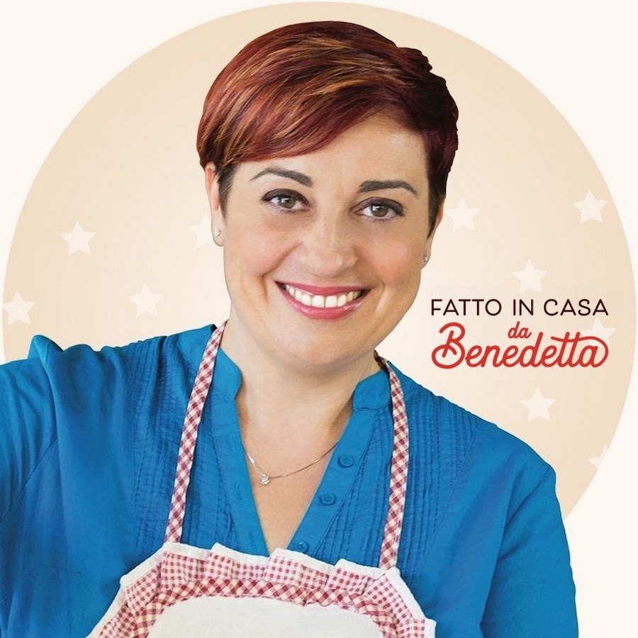 Benedetta Rossi sorride in grembiule a quadretti bianchi e rossi su sfondo chiaro