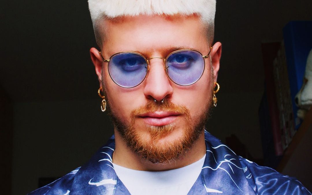 Riccardo Dose con occhiali dalle lenti azzurre e camicia a fantasia