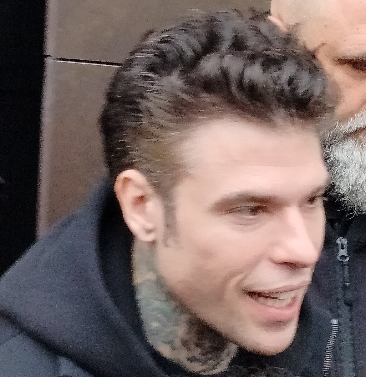 Fedez di profilo, capelli scuri tirati indietro e tatuaggi sul collo