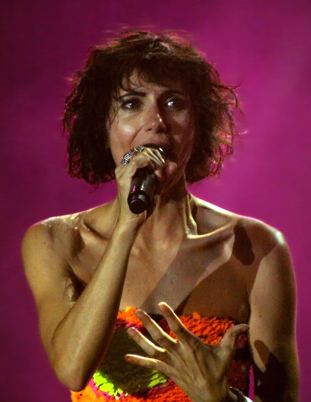 Giorgia canta al microfono sotto una luce rosa durante un concerto