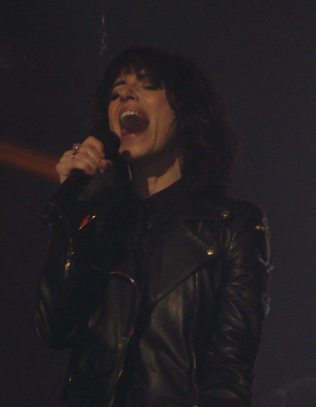 Giorgia canta al microfono su un palco, giacca di pelle nera e capelli ricci