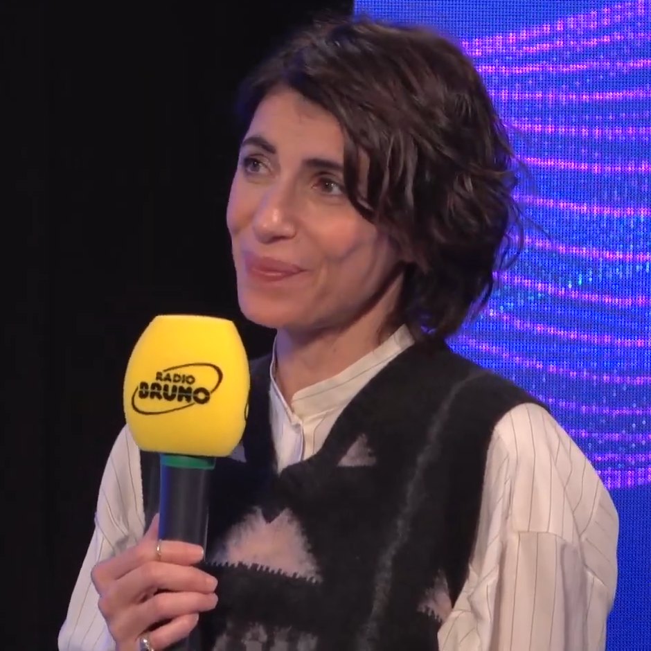 Giorgia sorride durante un'intervista, microfono giallo in mano