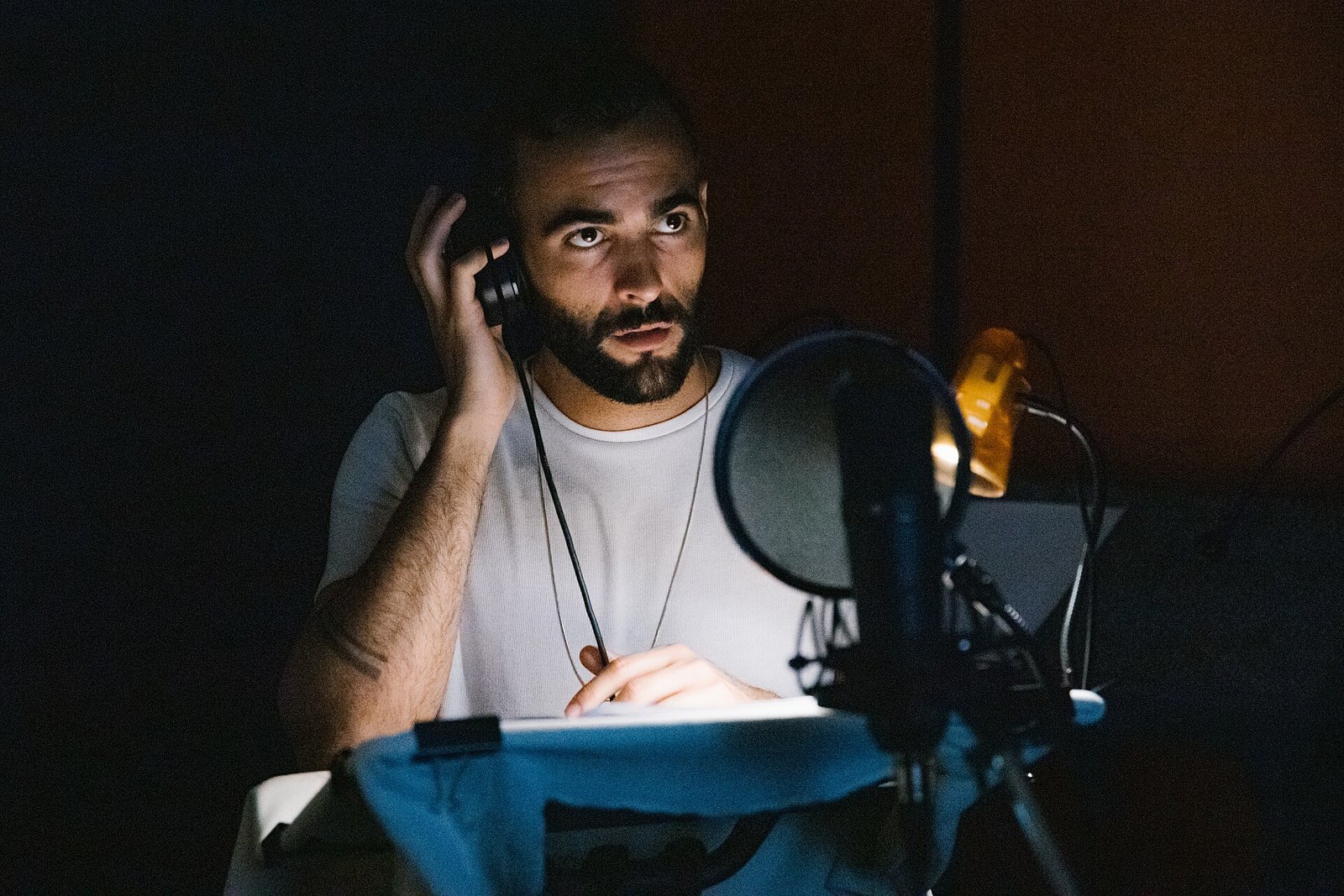 Marco Mengoni con le cuffie all'orecchio davanti a un microfono in studio