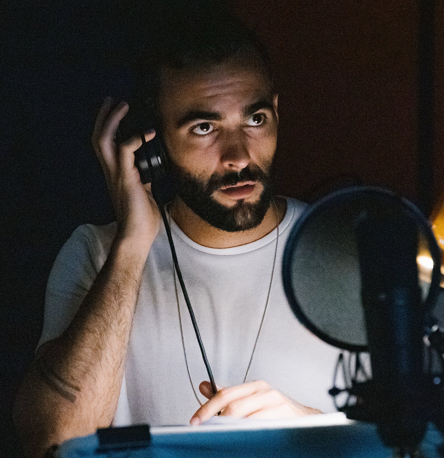 Marco Mengoni con una cuffia all'orecchio davanti a un microfono in studio