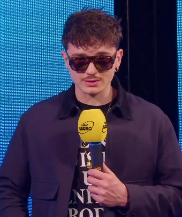 Olly con occhiali da sole scuri durante una intervista