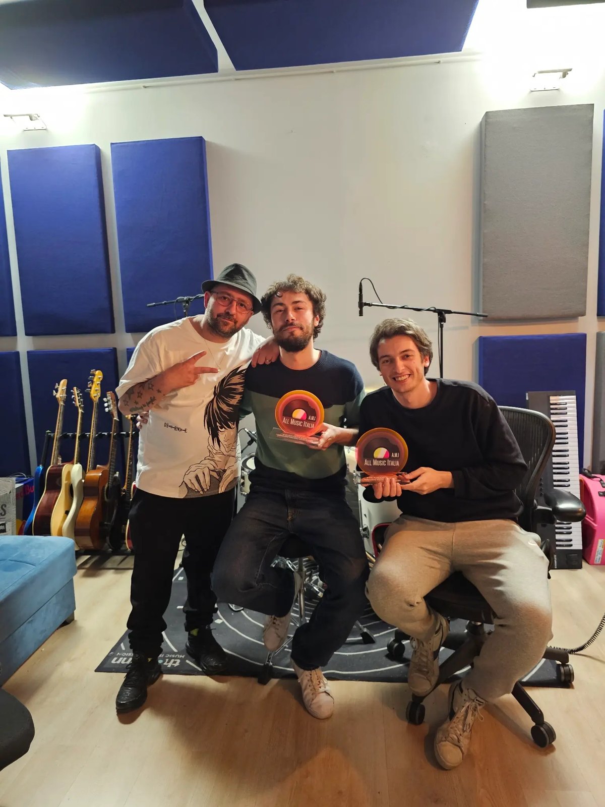 Riccardo Zanotti ed Elio Biffi dei Pinguini Tattici Nucleari sorridono in uno studio con due premi in mano