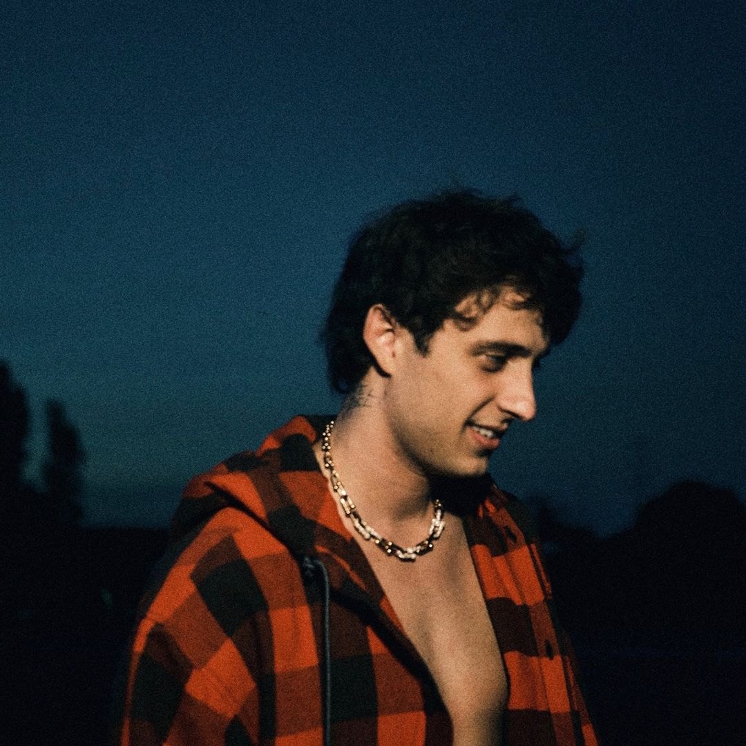 sangiovanni di profilo al tramonto, camicia a quadri aperta e collana di perline