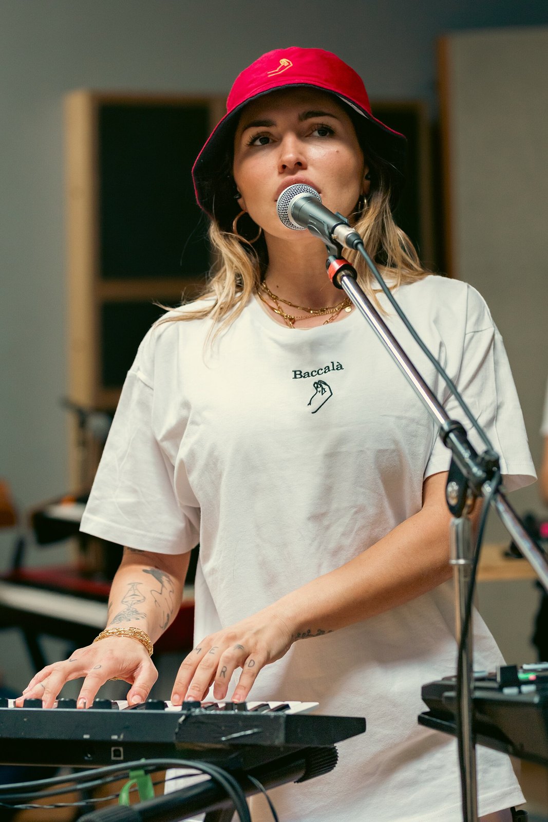 Serena Brancale canta al microfono con un cappello rosso, le mani su una tastiera