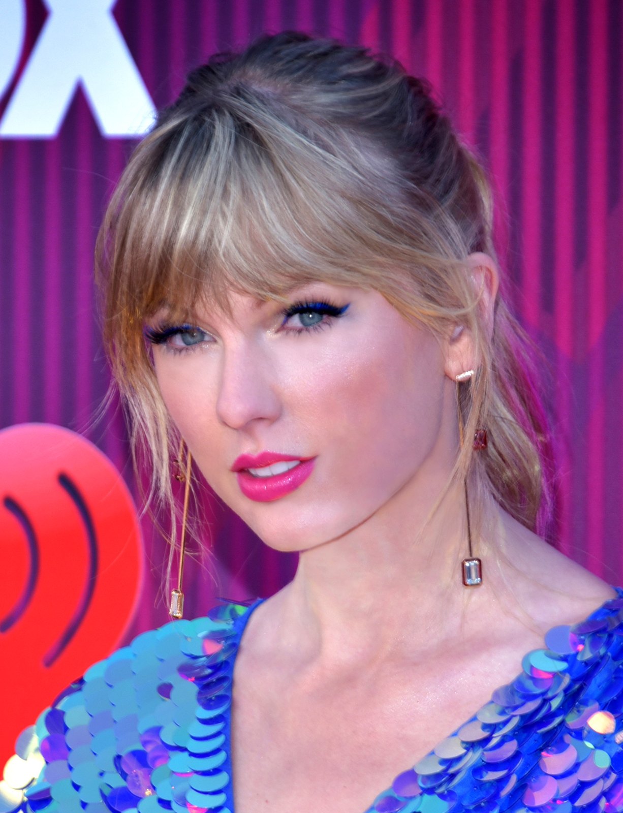 Taylor Swift in primo piano sul tappeto rosso, abito azzurro a paillettes