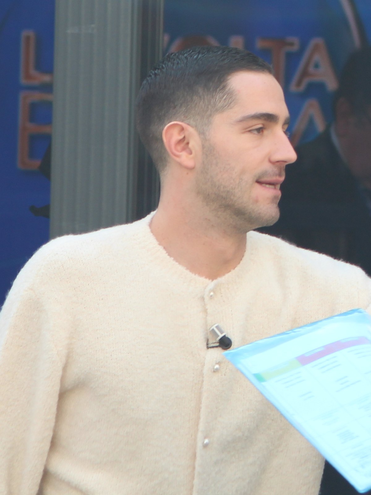 Tommaso Zorzi di profilo, con un cardigan bianco e il microfono appuntato