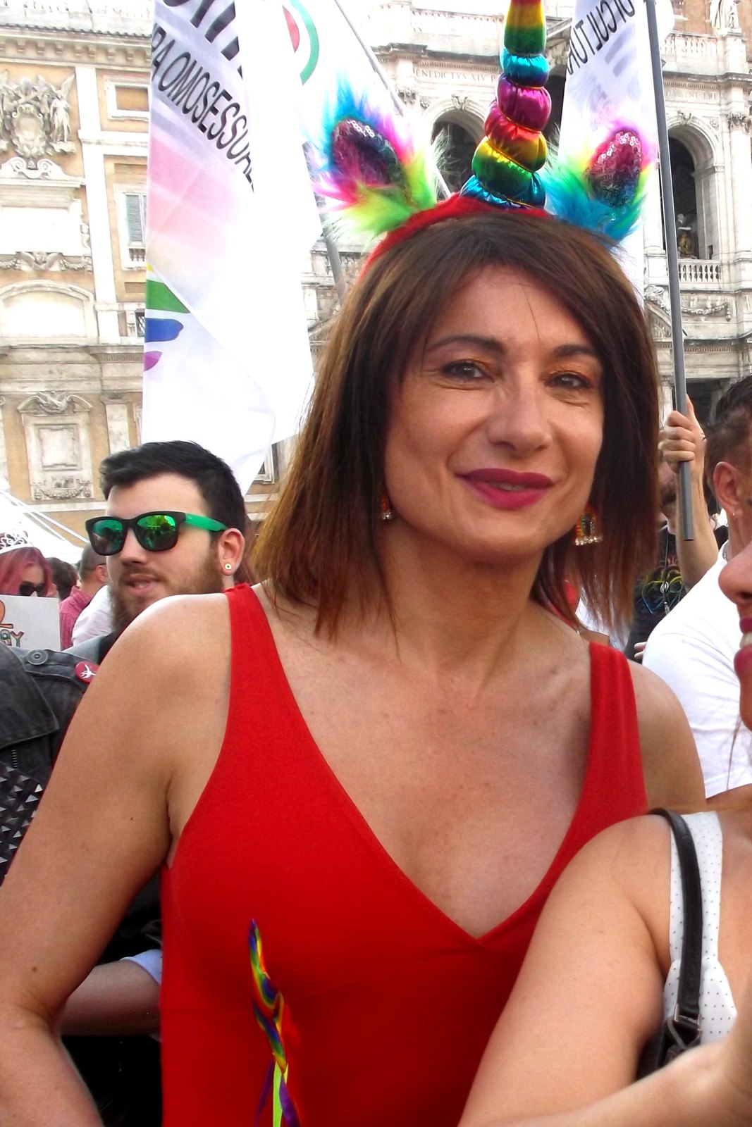 Vladimir Luxuria sorride in mezzo alla folla con un cerchietto colorato tra i capelli